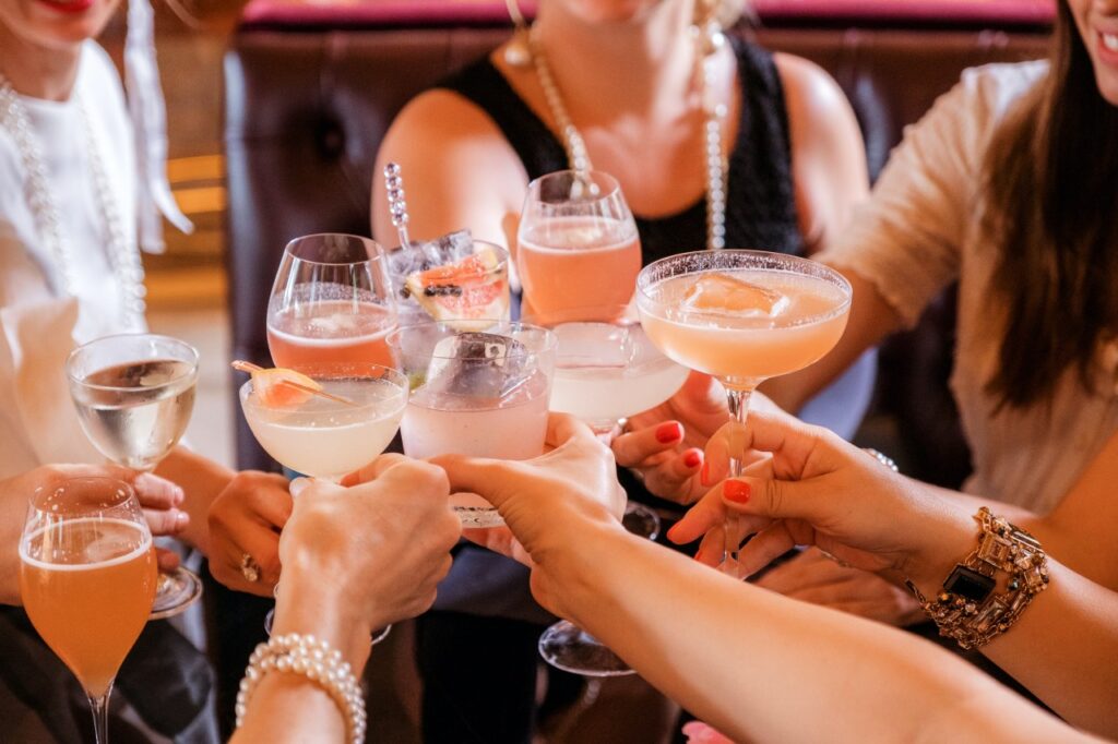 Friends clinks glasses with fancy cocktails at catered event
